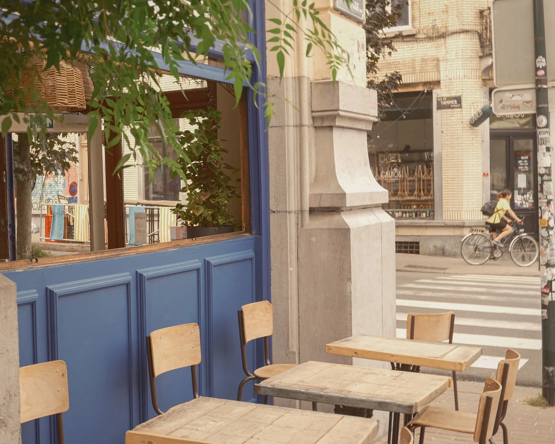 La terrasse de Bambin, rue des Tamines à Saint-Gilles : tables et chaises en bois devant la façade bleue de La Bagarre